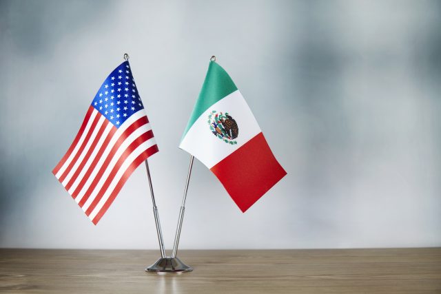 American and Mexican flag standing on the table with defocused background