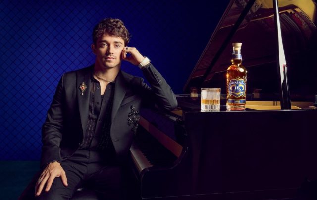 Charles Leclerc sat bedside a piano with a bottle of Chivas Regal on top.