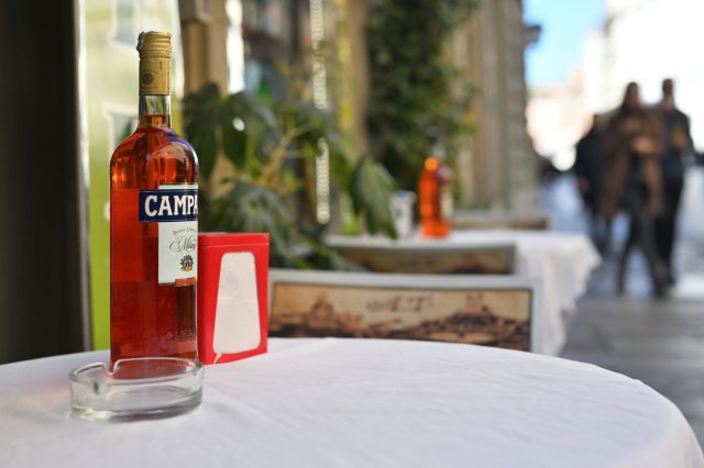 Rome, Italy - February 17, 2022: Campary bottle on table in the street at restaurant. Italian alcoholic liqueur in Rome, Italy